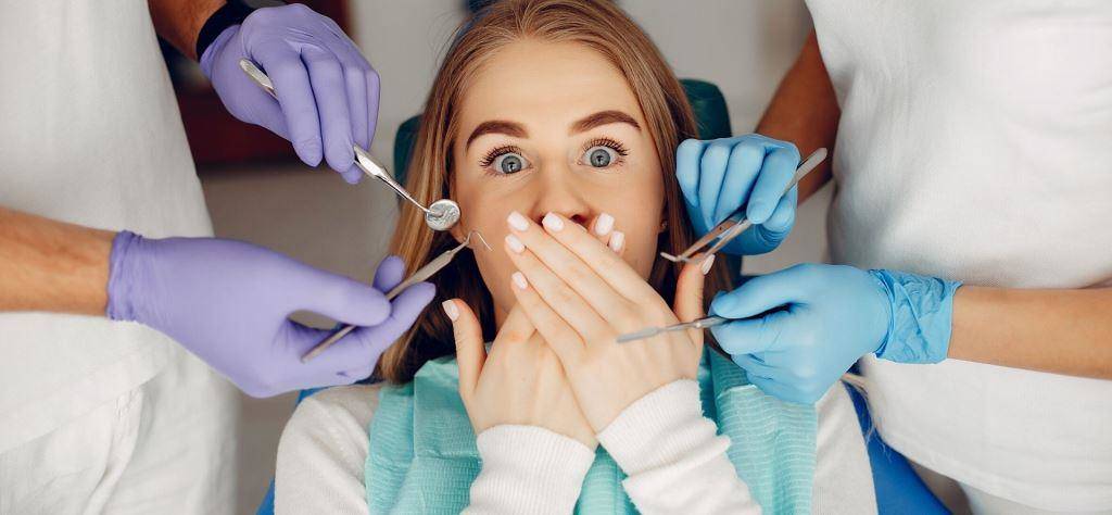 Pacjent zakrywający usta, z narzędziami dentystycznymi w pobliżu