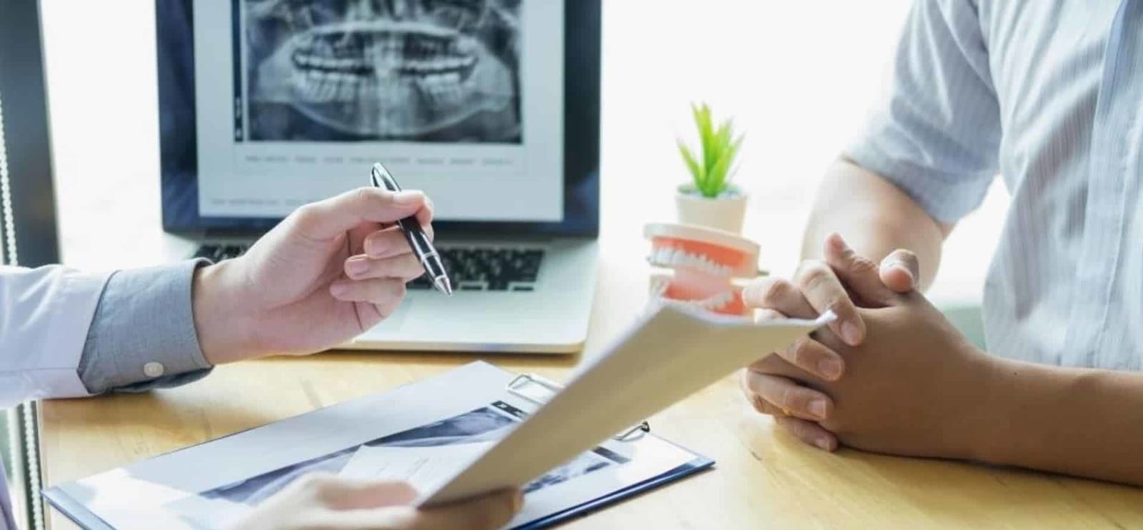 Dentysta omawiający informacje na podkładce przy laptopie
