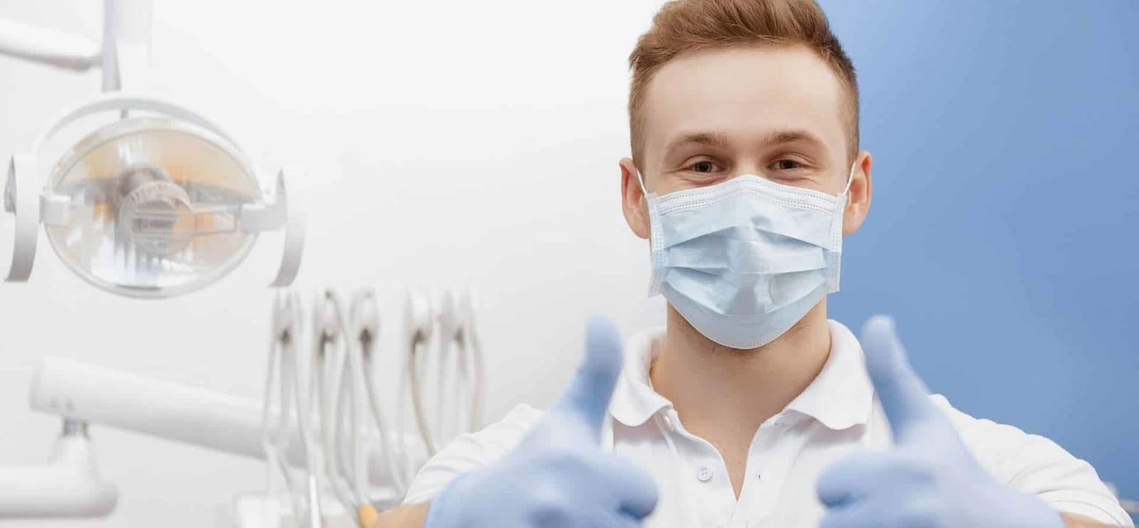 Dentysta w maseczce obok fotela dentystycznego