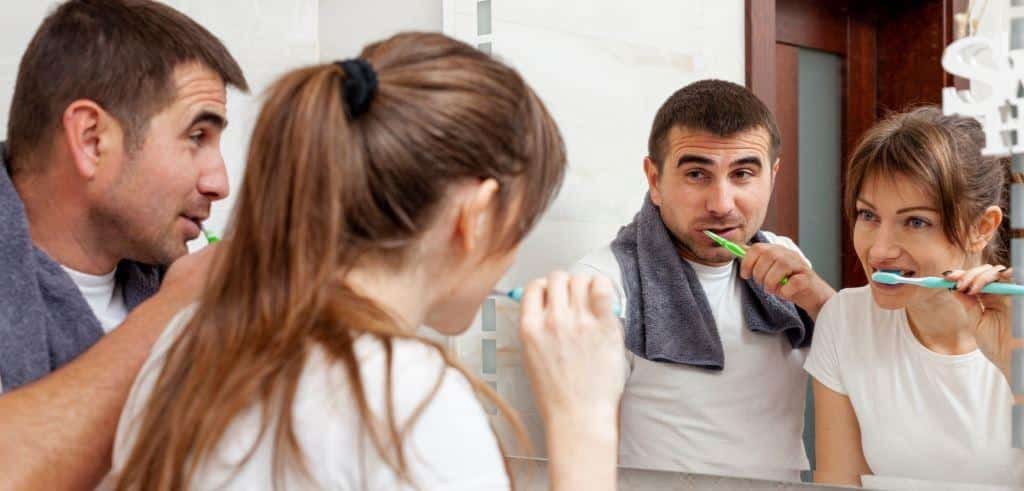 Osoby myjące zęby przed lustrem