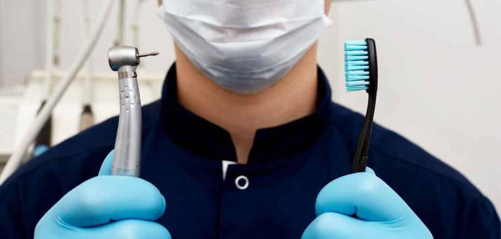 Osoba z zespołu trzymająca szczoteczkę i końcówkę stomatologiczną