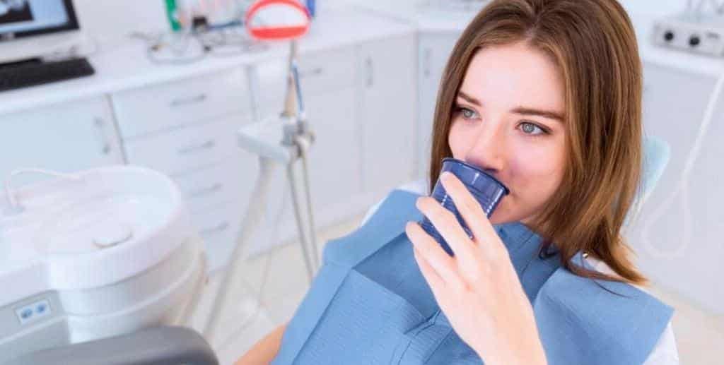 Pacjentka z kubkiem na fotelu dentystycznym