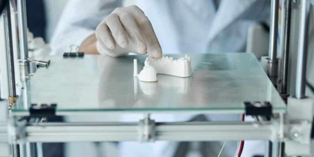 Dłoń w rękawiczce pracuje przy modelach zębowych na platformie urządzenia
