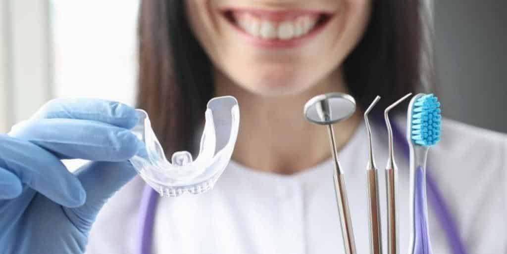 Osoba trzymająca przezroczystą szynę obok narzędzi dentystycznych