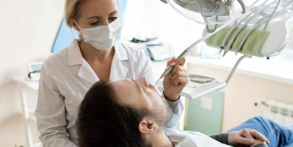 Dentystka badająca pacjenta na fotelu stomatologicznym
