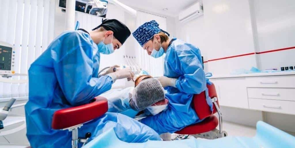 Dwie osoby z zespołu leczące pacjenta w fotelu stomatologicznym