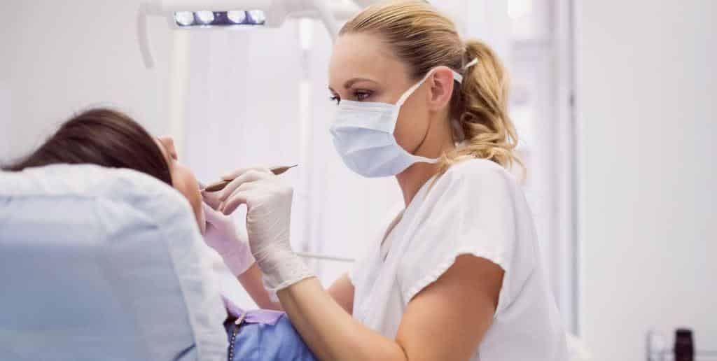 Dentysta badający pacjenta na fotelu dentystycznym