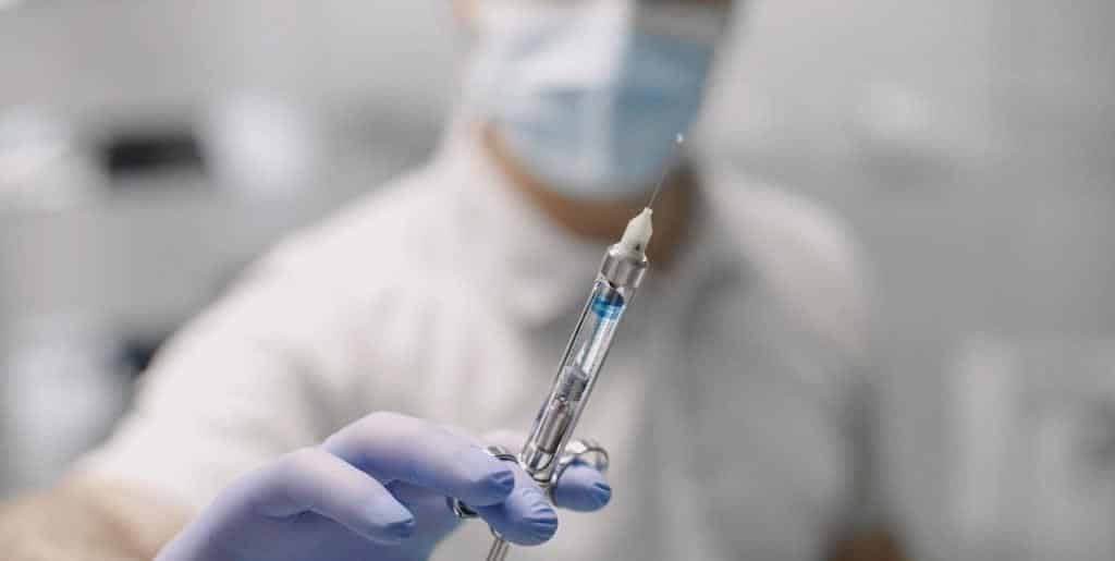 Strzykawka dentystyczna trzymana w dłoni w rękawiczce