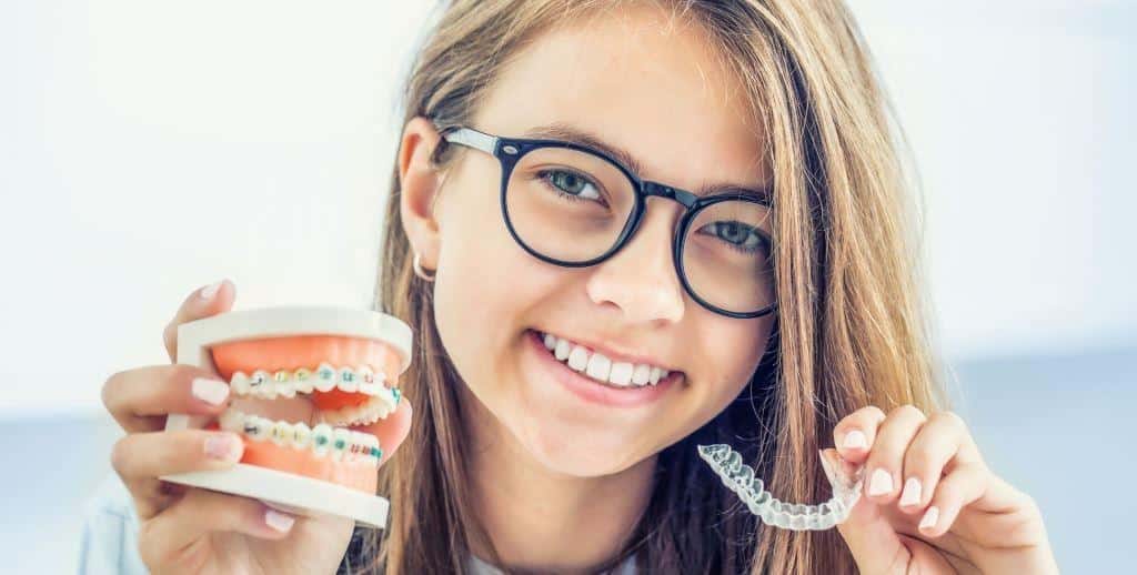 Osoba trzymająca model uzębienia i przezroczystą nakładkę