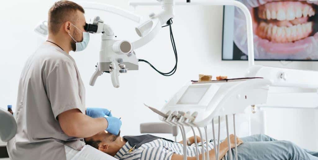 Dentysta korzystający z mikroskopu podczas leczenia pacjenta