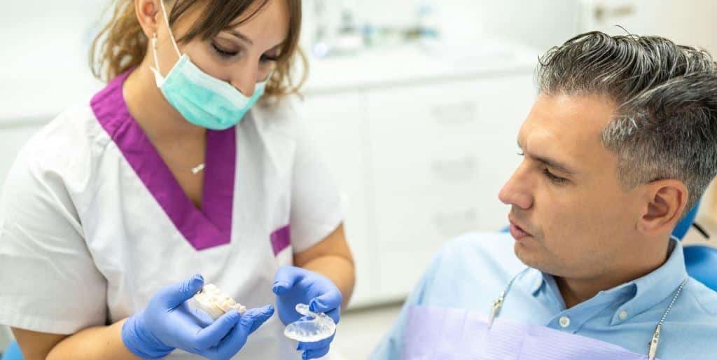 Lekarka pokazująca pacjentowi model zębów i przezroczystą szynę
