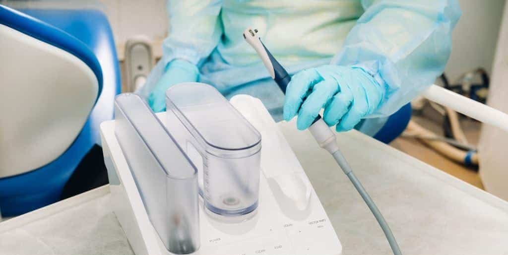 Osoba w rękawiczkach trzyma narzędzie przy unicie stomatologicznym