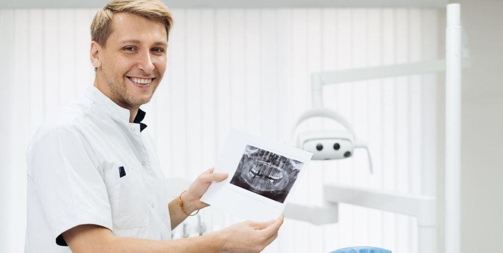 Uśmiechnięty dentysta trzymający zdjęcie RTG