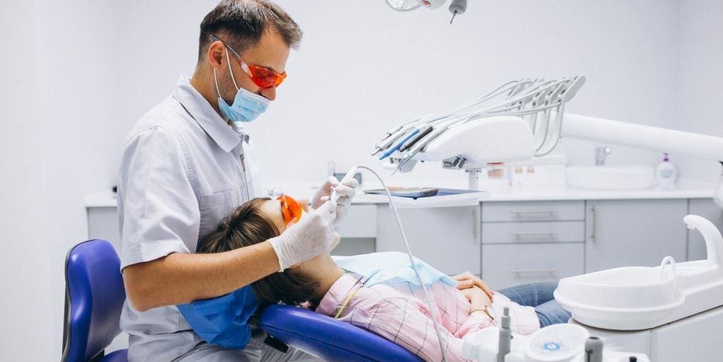 Lekarz bada pacjentkę w okularach ochronnych