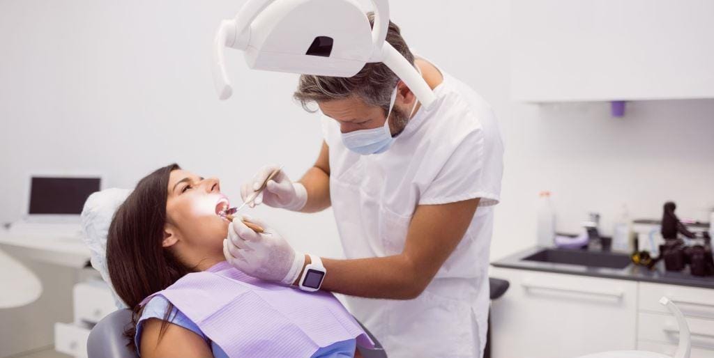 Dentysta badający pacjenta na fotelu dentystycznym