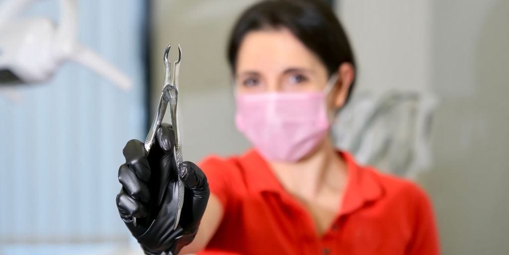 Lekarka w maseczce trzymająca kleszcze dentystyczne