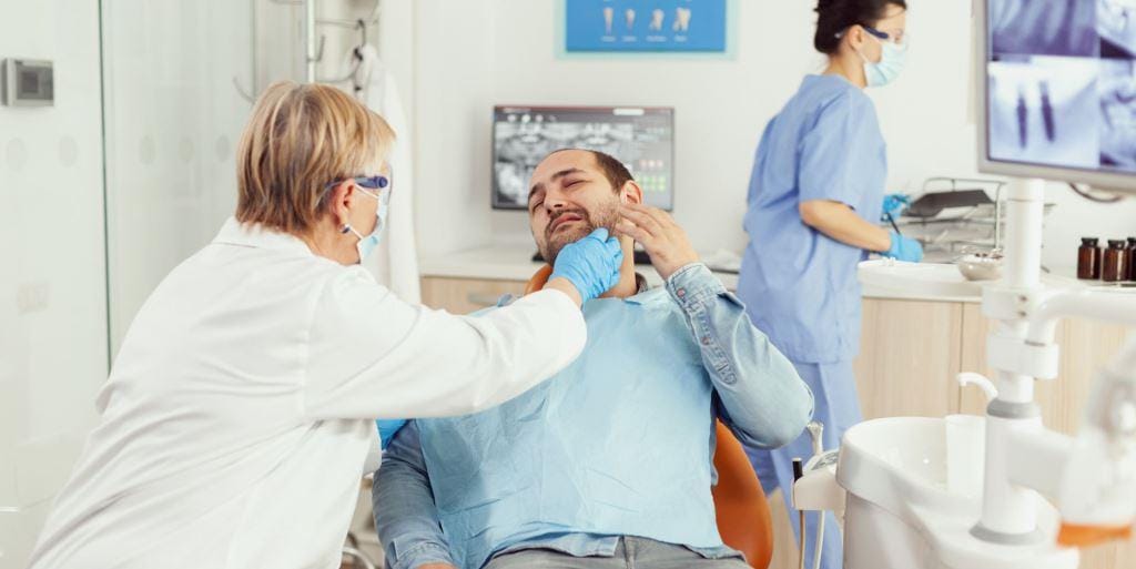Dentystka bada okolicę żuchwy pacjenta
