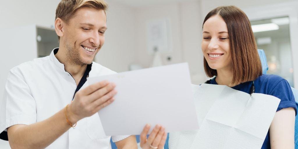 Dentysta i pacjentka wspólnie oglądają dokumenty