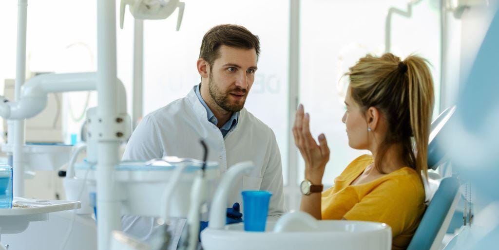 Pacjentka rozmawiająca z dentystą przy fotelu