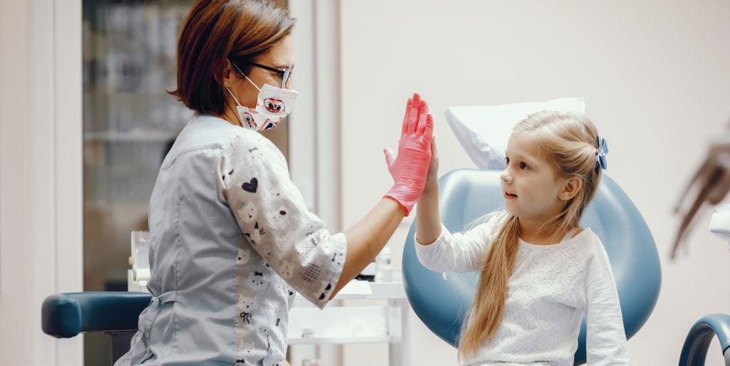 Dziecko i osoba z zespołu stomatologicznego przybijające piątkę