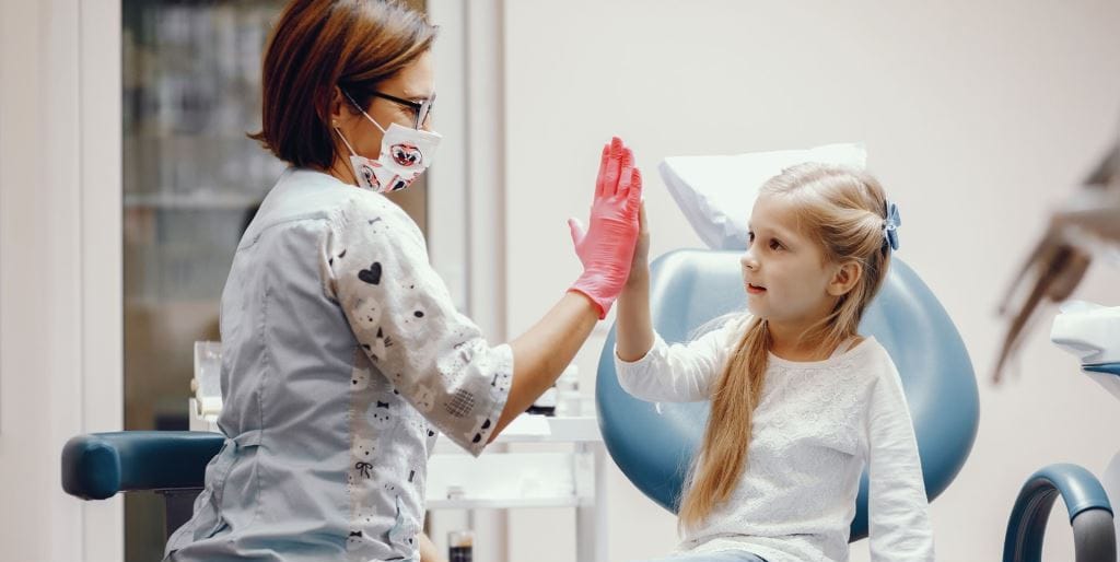 Dziecko i osoba z zespołu stomatologicznego przybijają piątkę