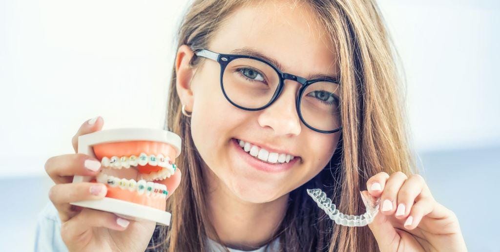Kobieta trzymająca model uzębienia i przezroczystą nakładkę