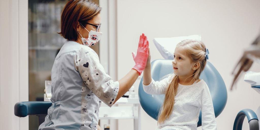 Dziecko przybijające piątkę osobie z zespołu stomatologicznego