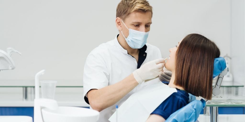 Dentysta badający pacjenta na fotelu dentystycznym