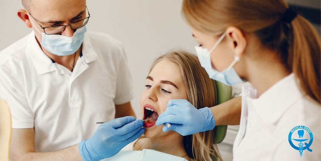 Dwie osoby z zespołu stomatologicznego badają pacjentkę