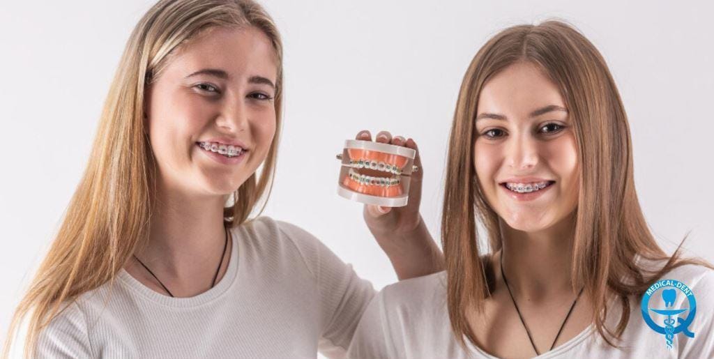Dwie osoby z aparatami na zębach, jedna trzyma model uzębienia