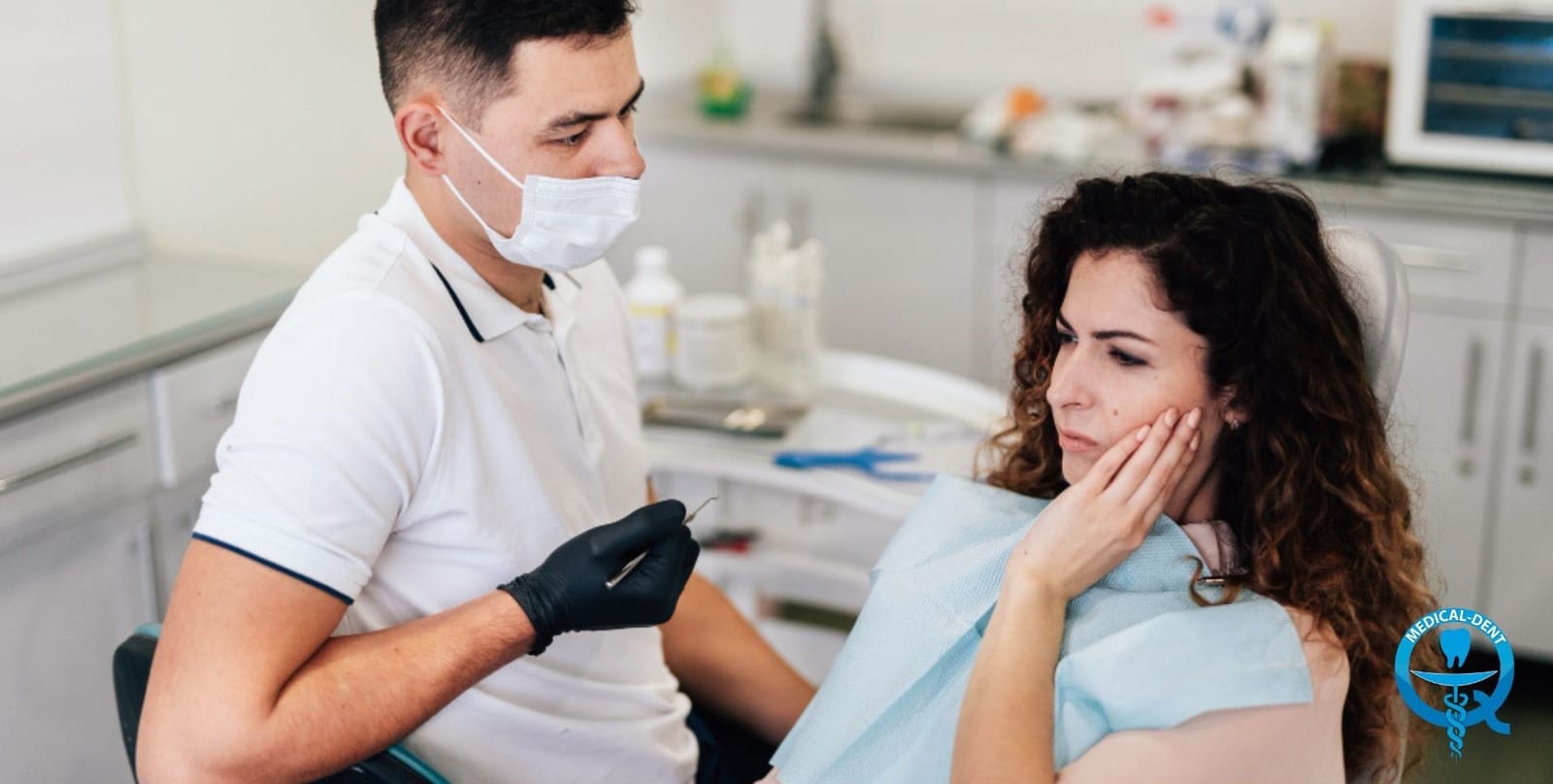 Dentysta rozmawia z pacjentką trzymającą dłoń przy żuchwie