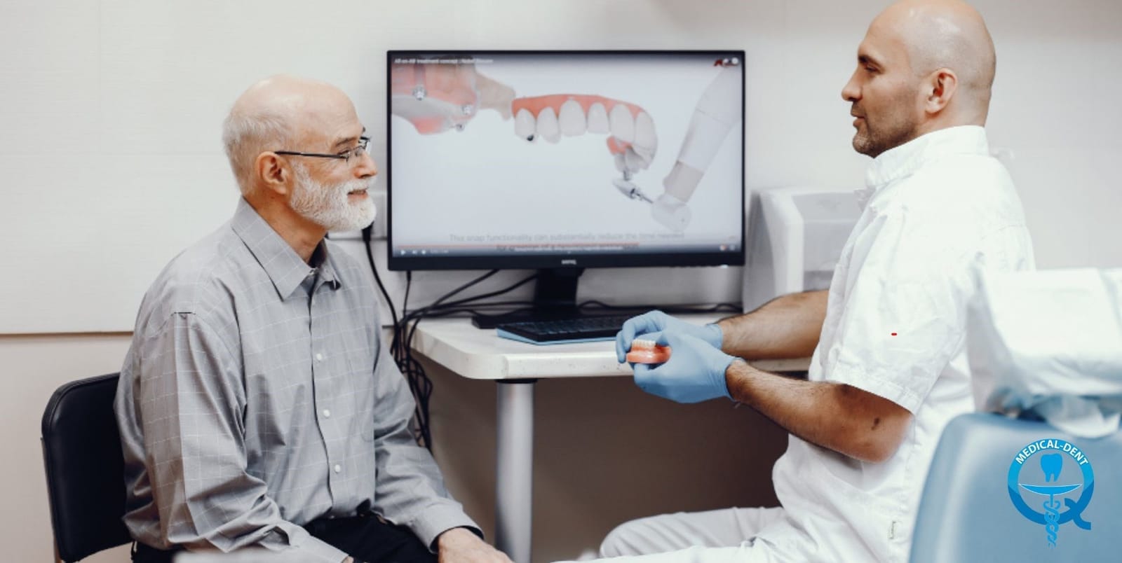 Dentysta omawiający z pacjentem obrazy na ekranie