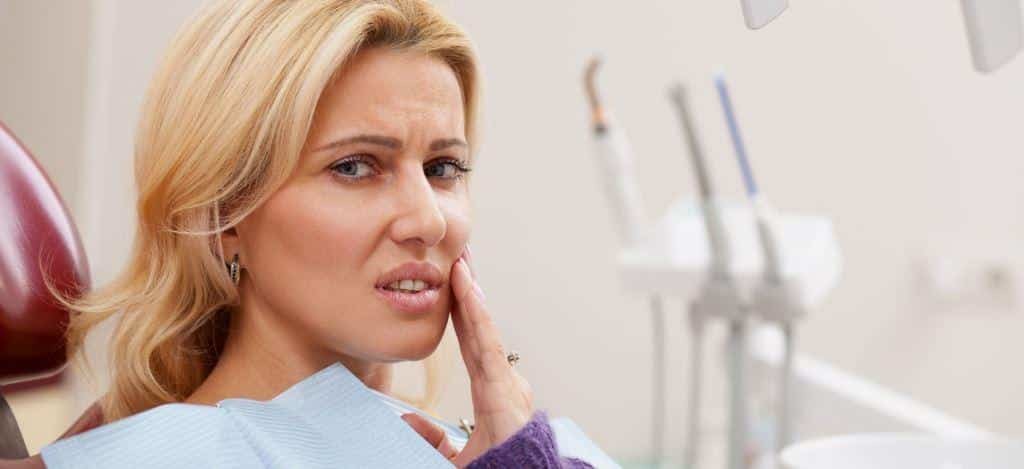 Pictura înfățișează o femeie matură, cu părul blond, purtând o cămașă albastră, așezată în scaunul unui dentist. Femeia își duce mâna la obraz și pare gânditoare sau ușor anxioasă. Instrumentele dentare sunt vizibile în fundal.
