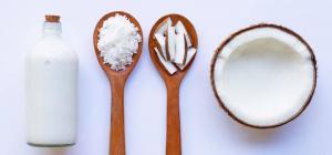Obraz przedstawia trzy drewniane łyżki i szklany pojemnik wypełnione produktami naturalnymi, najprawdopodobniej stosowanymi do higieny jamy ustnej. Na pierwszej łyżce znajduje się sól, na drugiej patyczki higieniczne, a w trzeciej misce widać białą, gęstą substancję, prawdopodobnie olej kokosowy.
