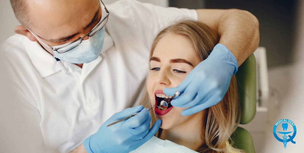 A dentist wearing goggles and a protective mask performs a dental procedure on a young patient lying in a dental chair.