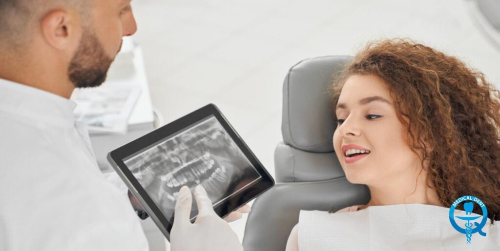 Dentysta w białym fartuchu pokazuje pacjentce siedzącej na fotelu stomatologicznym zdjęcie rentgenowskie zębów wyświetlone na tablecie, klinika Medical-Dent w UK.